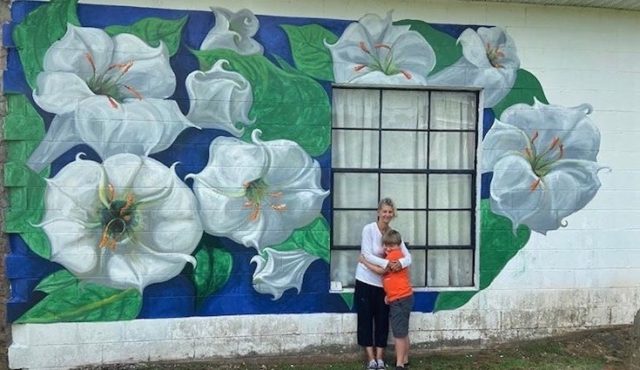 Photo of artist Melody Davis with grandson in front of her floral mural